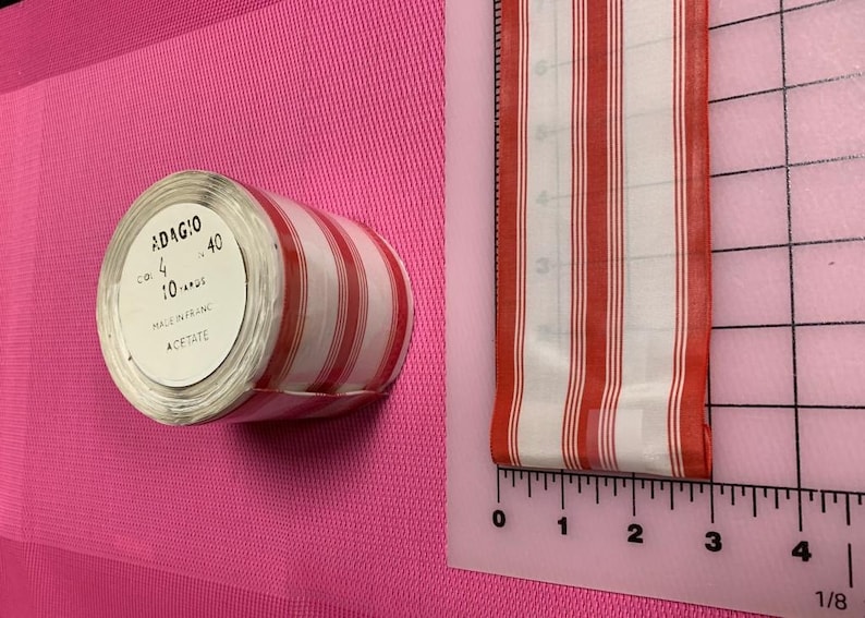 May include: A roll of red and white striped ribbon labeled "ADAGIO 40" with the text "COL. 4 10..." and "MADE IN FRANCE ACETATE".