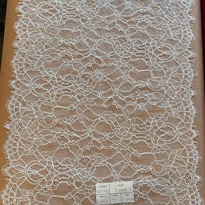 May include: White lace fabric with a floral pattern. The fabric is 14 inches wide and has an order number of P77908. The color is Ivory.
