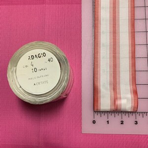 May include: A roll of red and white striped ribbon with a label that reads "ADAGIO CO! 4 40 10 YARDS MADE IN FRANC ACETATE".