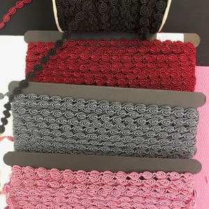 May include: Four spools of decorative trim with a rose pattern. The trim is available in black, red, gray, and pink.