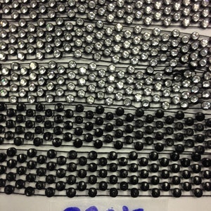 May include: Close-up of black and clear round beads sewn onto a black mesh fabric. The back of the fabric is visible, showing the black beads.