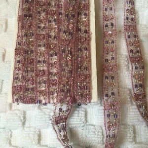 May include: Pink and purple beaded trim with a sheer fabric base. The trim is made of small beads and sequins.