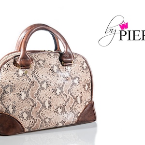 May include: A brown and beige snakeskin patterned handbag with brown leather trim and a top handle. The bag has a zipper closure and a gold metal accent.