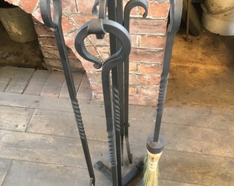 May include: A black metal fireplace tool set with a stand, including a poker, shovel, tongs, and a brush. The tools are all decorated with ornate swirls.