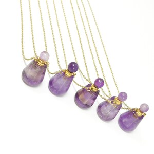 May include: Six amethyst gemstone perfume bottles on gold chains. The bottles are teardrop shaped and have gold caps.