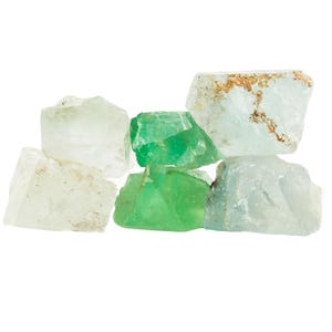 Op de afbeelding: Een groep van zes groene en heldere fluorietkristallen. De kristallen zijn van verschillende groottes en vormen, sommige hebben een ruwe, natuurlijke textuur.
