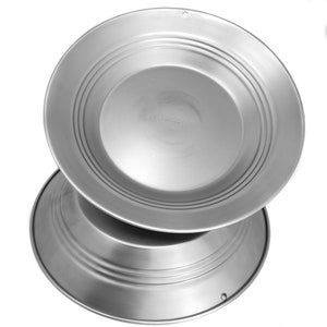 Puede incluir: Dos platos metálicos apilados, de color plateado brillante. Cada plato tiene un borde ligeramente elevado con ranuras concéntricas. Los platos tienen un diseño simple y utilitario, adecuado para servir alimentos. Los platos están hechos de un metal duradero.