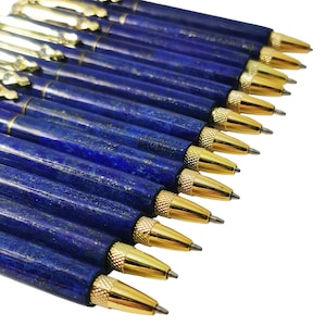 May include: A selection of blue pens with gold-coloured detailing. The pens feature a dark blue, textured barrel and a gold-coloured tip. The pens are arranged diagonally against a white backdrop.