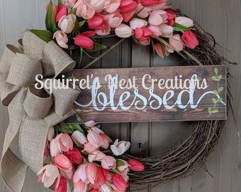 Może przedstawiać: Wianek z różowych i białych tulipanów z kokardą z juty i drewnianym szyldem z napisem "Squirrel's Nest Creations Blessed".