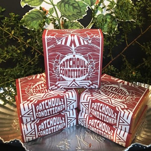 May include: A stack of four red and white rectangular bars of soap with the text "Patchouli Conditioner" printed on each bar.