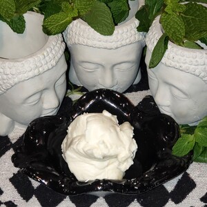 Op de afbeelding: Een witte keramische kom met een zwarte rand en een swirl-ontwerp staat op een zwart-wit geblokt oppervlak. Een witte, romige substantie vult de kom.