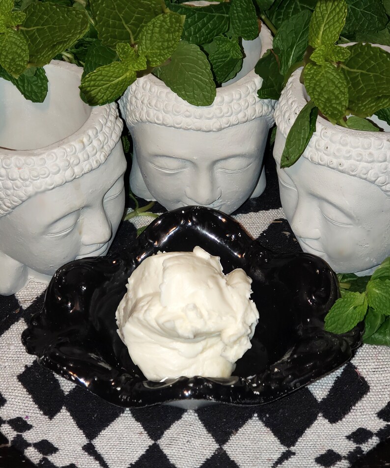 Op de afbeelding: Een witte keramische kom met een zwarte rand en een swirl-ontwerp staat op een zwart-wit geblokt oppervlak. Een witte, romige substantie vult de kom.