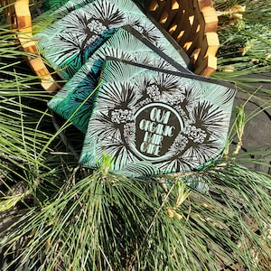 May include: A stack of green and black hair care product boxes with a pine tree design and the text "OUA ORGANIC HAIR CARE" on the top box.