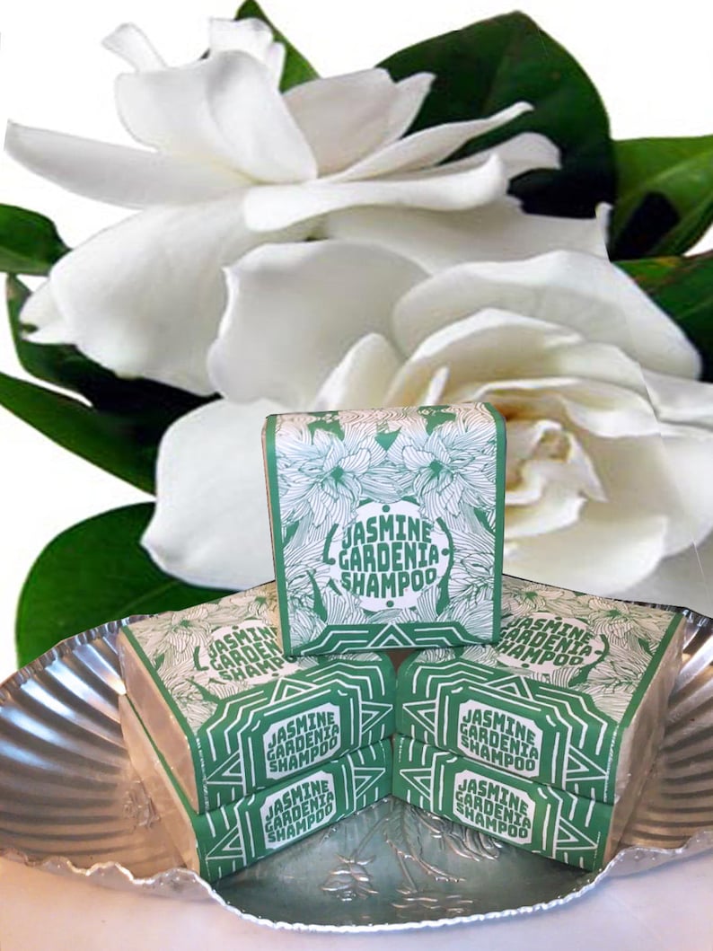 Puede incluir: Una pila de cinco jabones en barra verde y blanco con el texto "Jasmine Gardenia Shampoo" en cada barra. Los jabones est&aacute;n sobre una bandeja plateada.