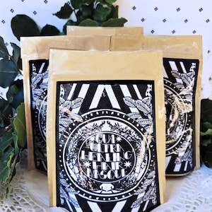 Op de afbeelding: Drie bruine papieren zakjes met zwarte en witte etiketten. Het etiket toont een zwart-witte illustratie van een bebladerde tak met de tekst "GUA ULTRA HEALING HAIR MASQUE".