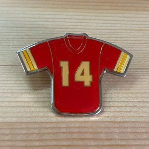 Puede incluir: Un pin de camiseta de f&uacute;tbol roja y dorada con el n&uacute;mero 14 en la parte delantera.