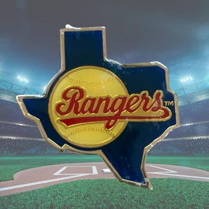 Może przedstawiać: Przypinka drużyny baseballowej Texas Rangers w kształcie stanu Teksas. Przypinka przedstawia żółtą piłkę do baseballu z napisem "Rangers" w czerwonym skrypcie. Kontur stanu jest niebieski ze złotą obwódką.
