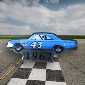 May include: A blue 1967 Plymouth race car with the number 43 on the side. The car is on a checkered flag finish line.