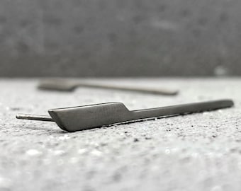 May include: A pair of silver earrings with a simple, straight design. The earrings are made of a thin, flat metal and have a slightly angled edge.