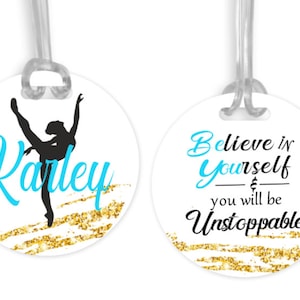 May include: Two round luggage tags with a gold glitter background. One tag features a silhouette of a dancer with the name "Karley" in blue script. The other tag has the text "Believe in yourself & you will be Unstoppable" in black script with blue accents.