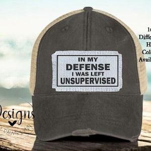 May include: A black and tan trucker hat with a white patch that reads "In my defense I was left unsupervised".