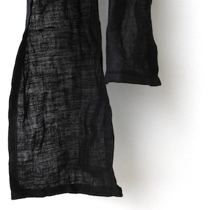 Close-up of lain hemmed ends of a narrow black linen scarf.