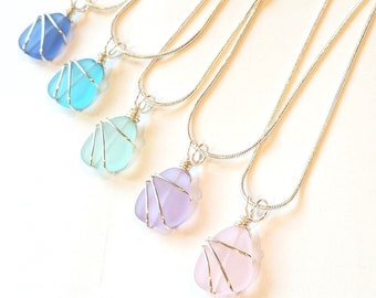 Può includere: Cinque collane con catena d'argento con ciondoli in vetro di mare di diversi colori. I ciondoli sono avvolti in filo d'argento e sono in tonalità di blu, verde, viola e rosa.