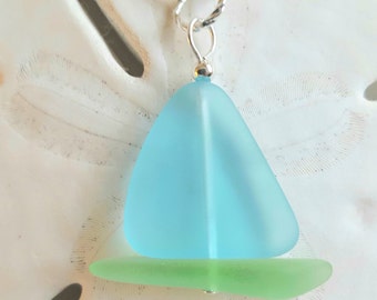 May include: A light blue sea glass sailboat pendant necklace with a green sea glass base. The pendant is on a silver chain.