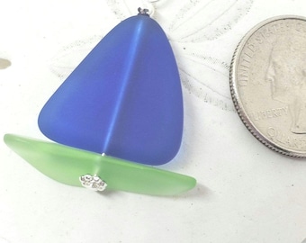 May include: A blue and green glass sailboat pendant necklace. The sailboat is made of sea glass and is about the size of a US quarter.