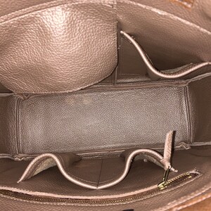 May include: The inside of a brown leather tote bag with multiple pockets and a zippered compartment.