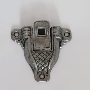 May include: Silver-toned metal latch with a decorative design. The latch has a square opening in the center and two holes on the sides.