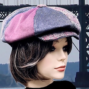 May include: A multi-paneled newsboy cap featuring a patchwork design of purple suede, blue pinstriped denim, and a red and black plaid fabric. The hat has a rounded crown with a central button detail and a short, stiff brim extending from the front.