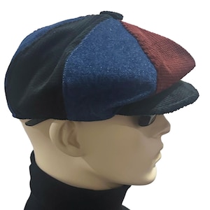 May include: A multi-colored newsboy cap featuring a patchwork design with panels of black, blue, and maroon fabric. The cap has a structured crown, a small top button, and a short, stiff brim, showcasing a mix of corduroy and denim-like textures.