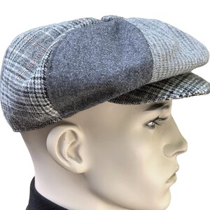 May include: A gray newsboy cap featuring a multi-textured design with panels of plaid fabric and solid charcoal gray wool-like material. The cap has a rounded crown, a short stiff brim, and a structured shape that sits atop a mannequin head.
