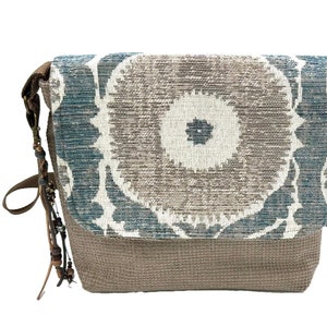 Crossbody messenger style purse with medallion design textured home decor fabric. Leather clip on tassel.