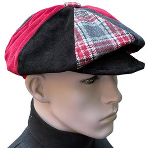 May include: A multi-panel newsboy cap featuring a combination of solid red and black fabric panels alongside a grey, black, and red plaid patterned panel. The cap includes a matching fabric-covered button at the top and a stiff, rounded brim.