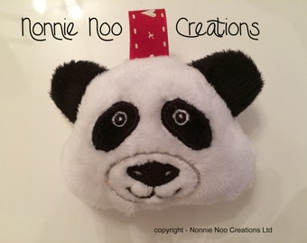 May include: A plush panda face with black ears, eyes, and nose, and a white body. A red and white polka dot ribbon is attached to the top. The text "Nonnie Noo Creations" is above the panda.