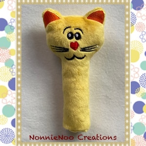 以下が含まれることがあります： オレンジ色の耳と赤いハート型の鼻を持つ、黄色のぬいぐるみ猫のガラガラ。ガラガラは赤ちゃんや幼児のために設計されています。