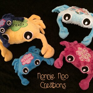 Pode incluir: Quatro brinquedos de peluche em forma de caranguejo com detalhes bordados. Os caranguejos são azuis, amarelos, cor-de-rosa e azul claro. Cada caranguejo tem um nome diferente bordado: "Crab", "Chloe" e mais dois.