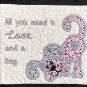 May include: A white quilted coaster with a pink and gray embroidered dog and the text "All you need is Love and a Dog".