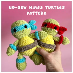 May include: Two handmade crochet plush toys resembling turtles with light green bodies and yellow bellies. One has a blue mask and wristbands, the other a red mask and wristbands. Both have brown belts and black eyes. Text reads: NO-SEW NINJA TURTLES PATTERN.