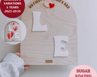 May include: A laser-cut wooden sign with the words "My First Valentine's Day" and the letters "LOVE" in white. The sign is decorated with two pink hearts and includes the years 2025 and 2028. The sign is labeled "Laser Ready! SVG File" and "Sugar Koated Designs".