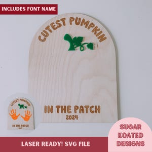 Könnte beinhalten: Ein lasergeschnittenes Holzschild mit dem Text "Cutest Pumpkin in the Patch 2024" in einer abgerundeten Bogenform. Das Schild ist mit einer grünen Kürbisranke und einem kleinen Handabdruck verziert.