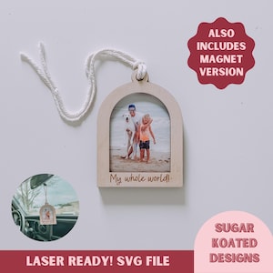 Peut inclure: Un cadre photo en bois découpé au laser avec une ouverture en arc, présentant une photo d'une famille avec son chien sur une plage. Le cadre est muni d'une ficelle pour l'accrocher et le texte "My whole world!" est gravé sous la photo. L'image comprend également une image plus petite du cadre accroché dans une voiture.