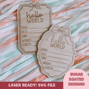 Puede incluir: Dos placas de madera para anunciar el nacimiento de un bebé con la inscripción "hello WORLD". Las placas tienen espacio para escribir el nombre, la fecha, la hora, el peso y la longitud del bebé. El fondo está decorado con cintas pastel.