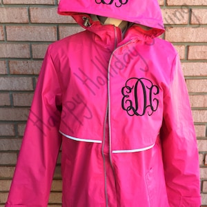 May include: A pink rain jacket with a white stripe and a black monogram "E.D.C." on the front and hood.