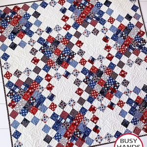May include: A red, white, and blue quilt with a geometric pattern. The quilt is made of squares and is quilted with a swirl design. The quilt is on a white surface. The text "BUSY HANDS QUILTS buy handmade" is in the lower right corner of the image.
