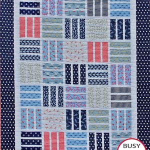 May include: A navy blue and white quilt with a nautical theme. The quilt is made up of various squares with different patterns, including anchors, sailboats, stripes, and seashells. The quilt is bordered with a navy blue fabric with white stars. The quilt is labeled "Busy Hands Quilts" in the bottom right corner.
