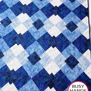 May include: A blue and white quilt with a geometric pattern. The quilt is made of squares and rectangles, and the pattern is created by alternating the colours of the squares. The quilt is quilted with a swirling pattern.