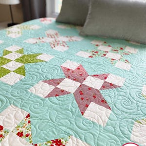 May include: A turquoise and white quilt with a star pattern and floral fabric squares. The quilt is quilted with a swirl pattern. The quilt is made by Busy Hands Quilts, buy handmade.